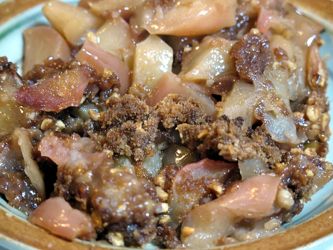 Close-up of baked apple crisp on a plate showing soft apple pieces and a brown crumbly oat topping photo_0
