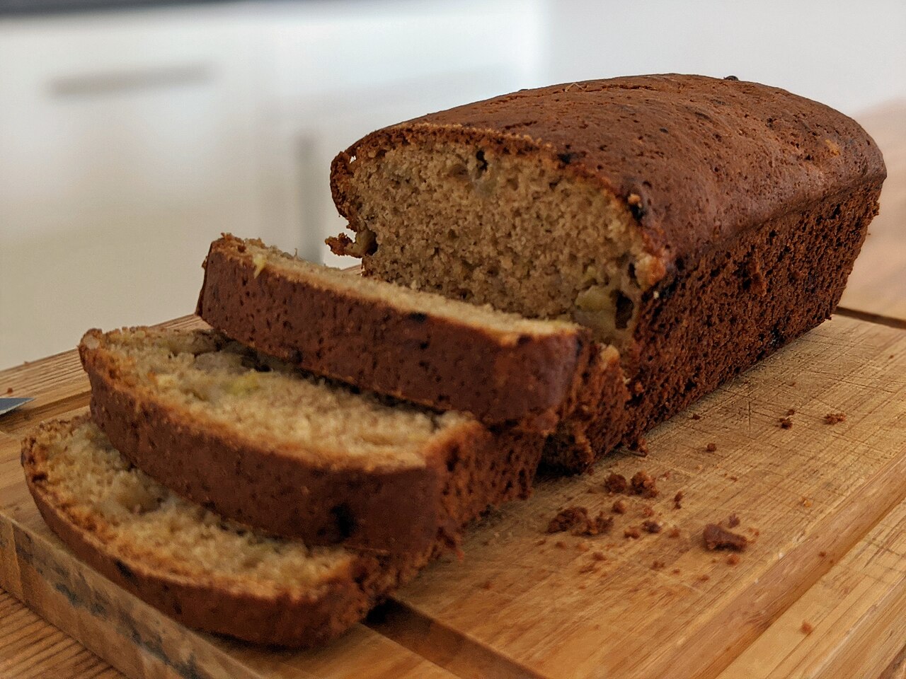 Banana bread loaf cut into thick slices on a wooden cutting board, showing the tender crumb photo_0 Banana bread loaf cut into thick slices on a wooden cutting board, showing the tender crumb photo_0
