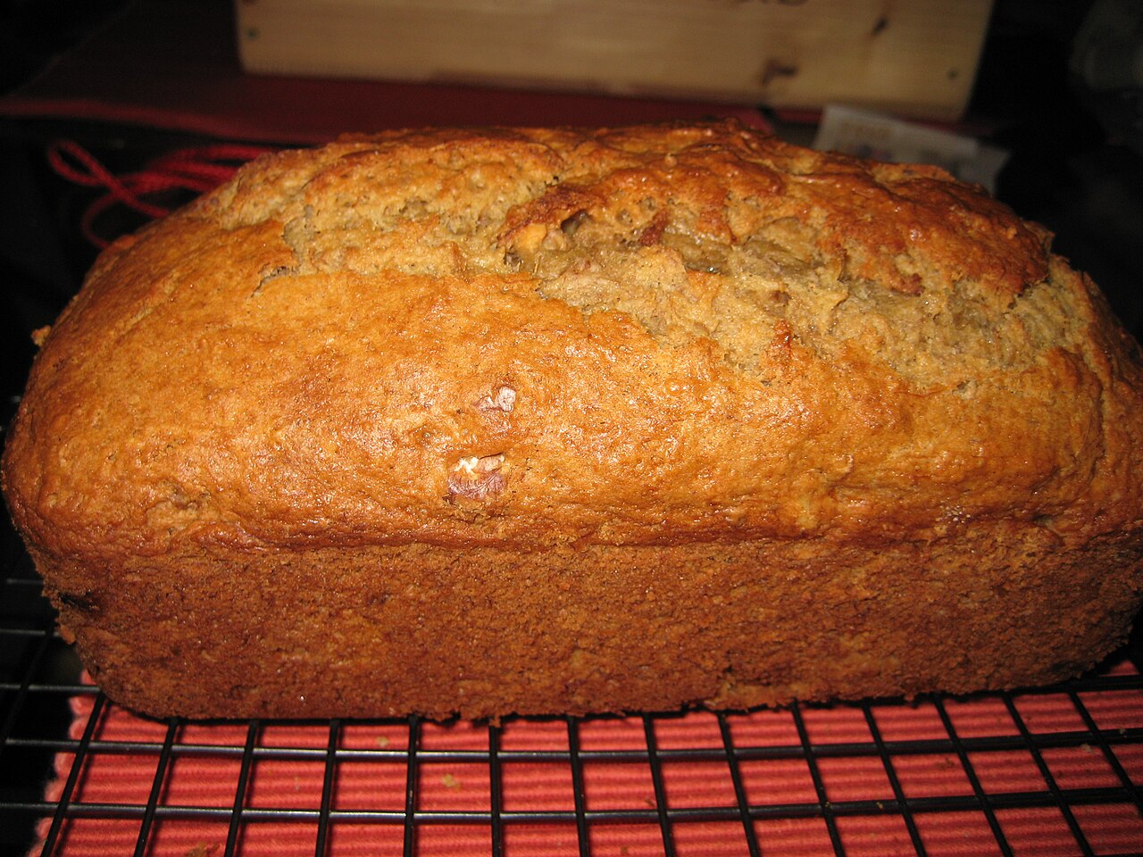 Whole golden-brown banana bread loaf with a cracked top cooling on a wire rack photo_0 Whole golden-brown banana bread loaf with a cracked top cooling on a wire rack photo_0